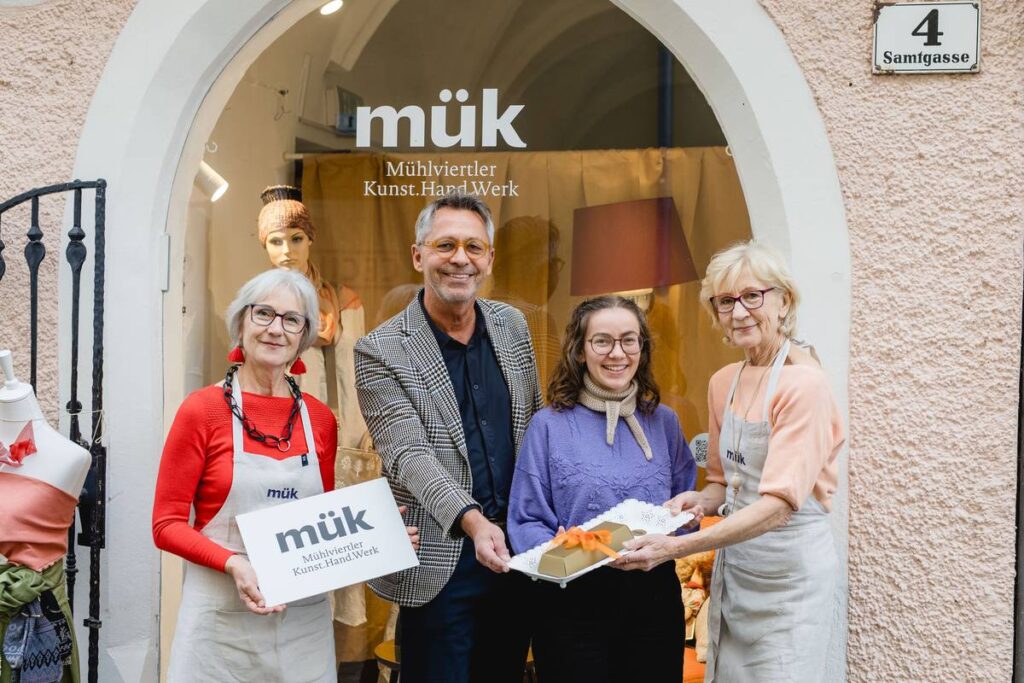 Mühlviertler Kunst.Hand.Werk: Vier Personen mit Schild und Geschenk vor Geschäft in Freistadt